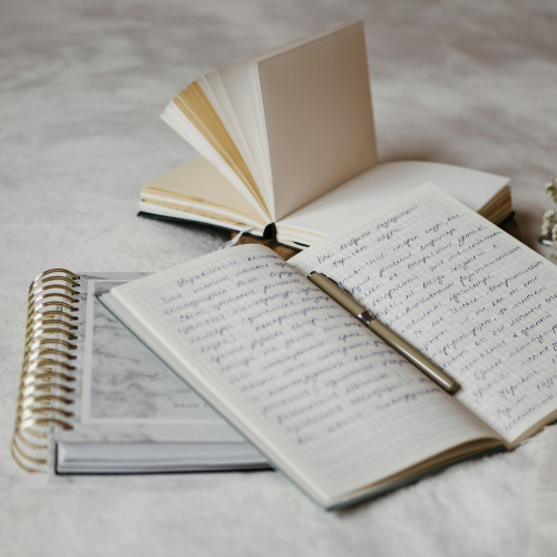Cadernos abertos com anotações manuscritas e caneta sobre superfície clara, representando o processo de como fazer um resumo de um livro.